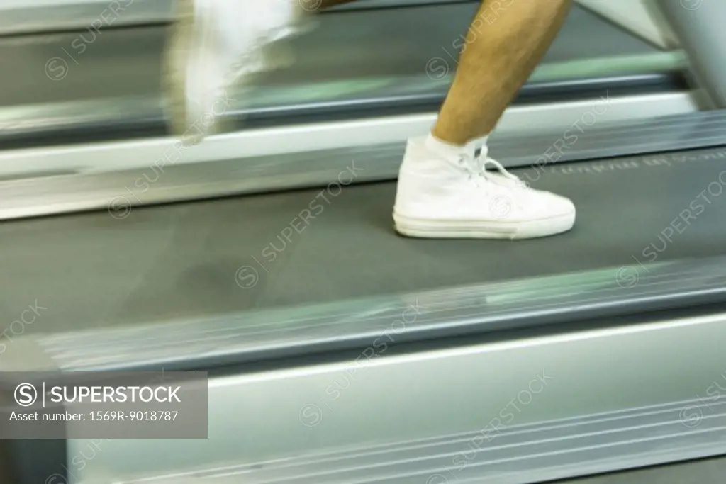 Man running on treadmill, close-up of feet