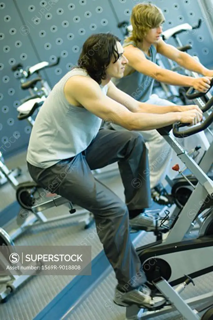 Two men riding exercise bikes