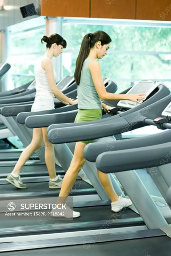 Two women walking on treadmills
