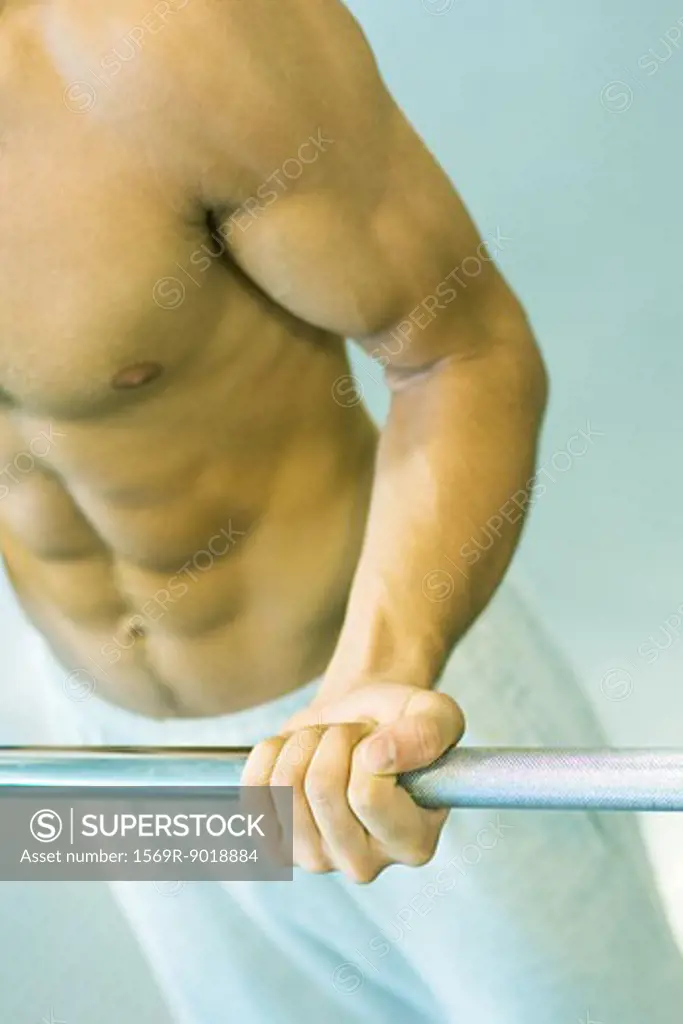 Man lifting barbell, close-up of mid section
