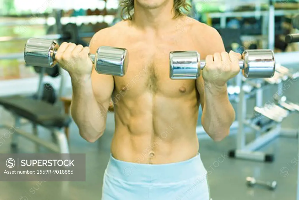Man lifting dumbbells, close-up of torso