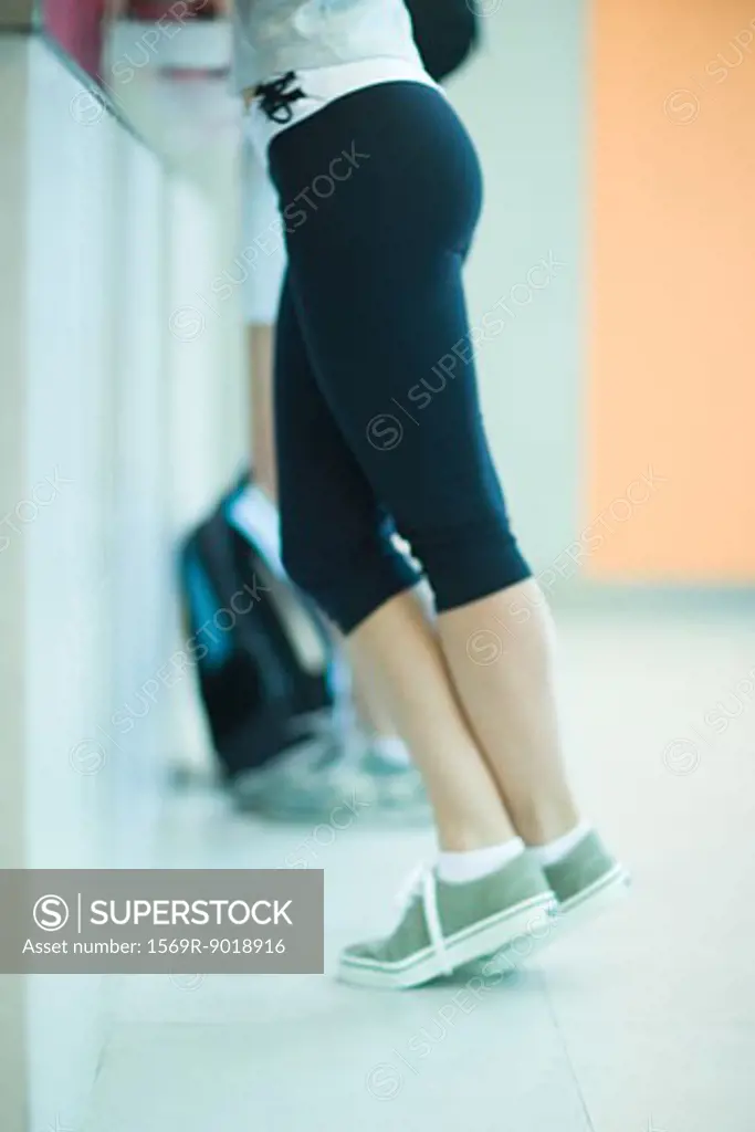 Young woman checking in at health club counter, waist down