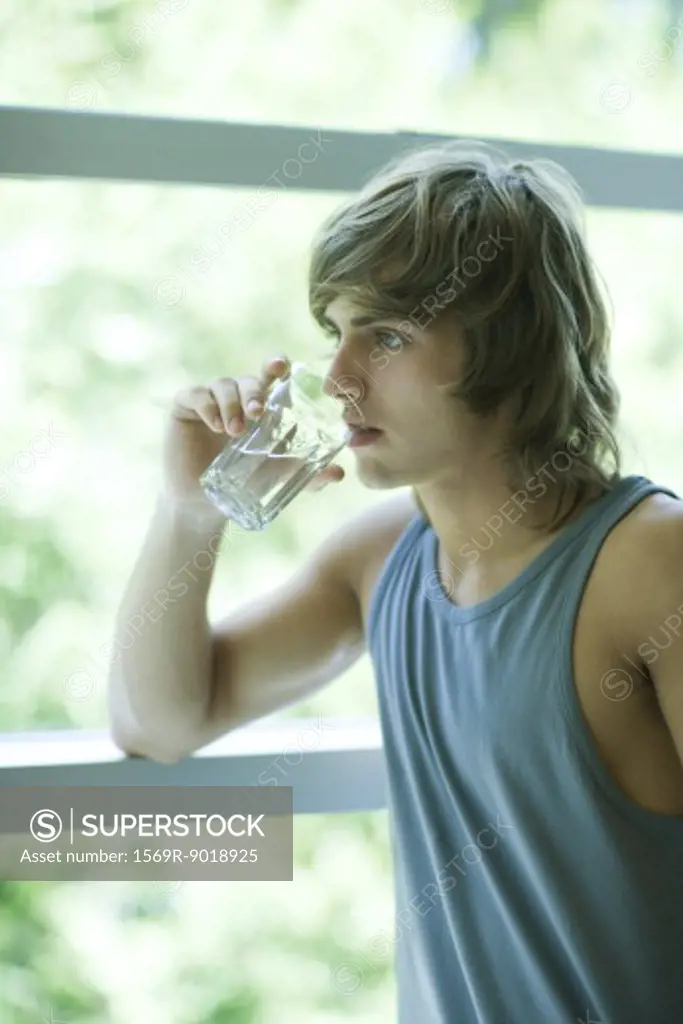 Young woman in exercise clothes drinking glass of water