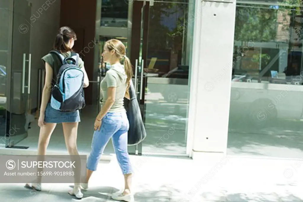 Two young women walking toward doorway together