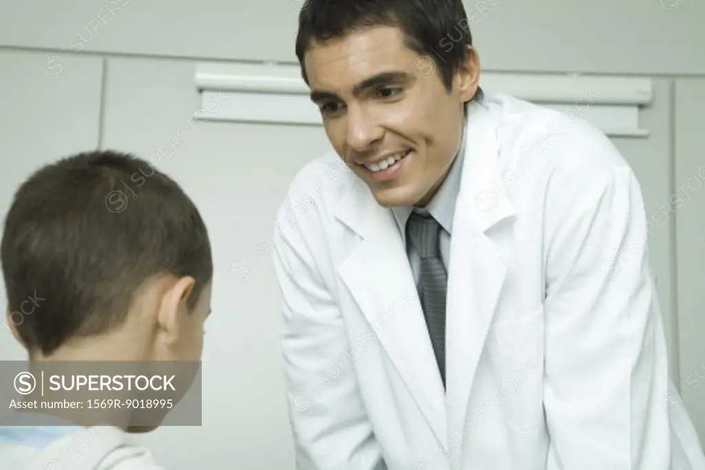 Doctor leaning forward, smiling at little boy