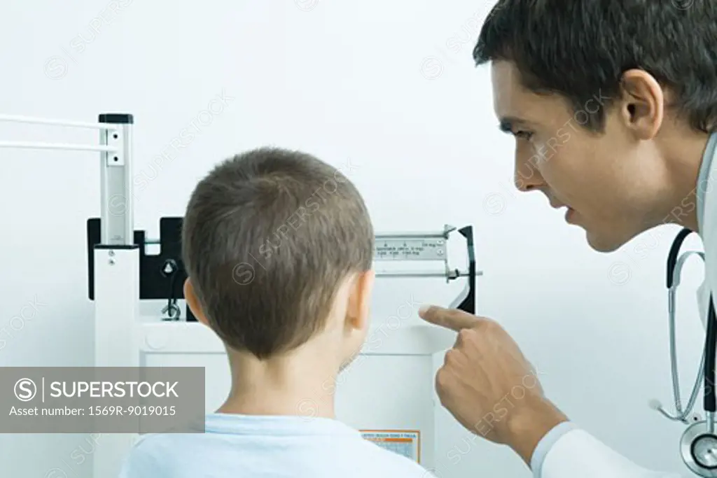 Doctor weighing boy during check-up