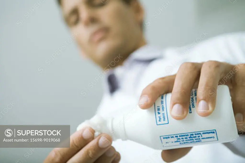 Doctor pouring antiseptic onto cotton ball