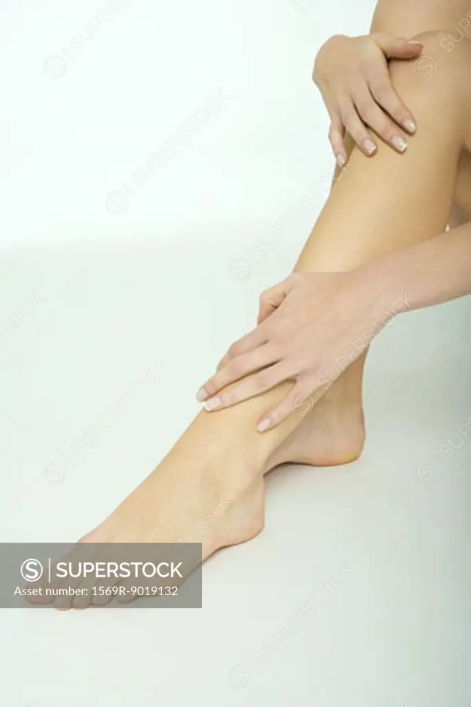 Woman touching legs, close-up, cropped view from knee down