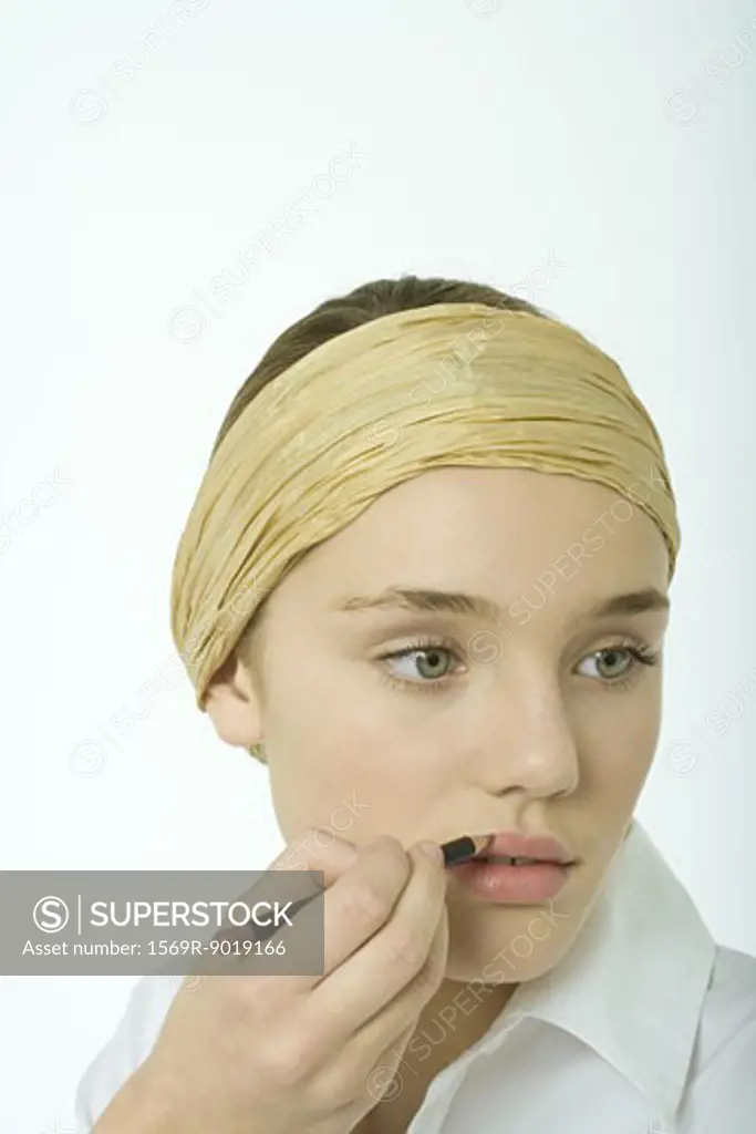 Teenage girl applying lipliner