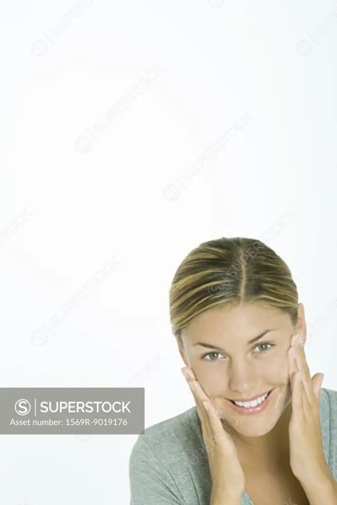 Woman washing face, smiling at camera