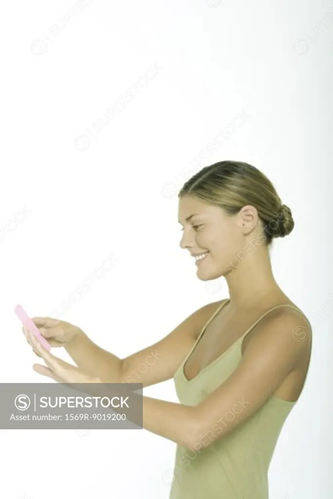 Young woman filing fingernails