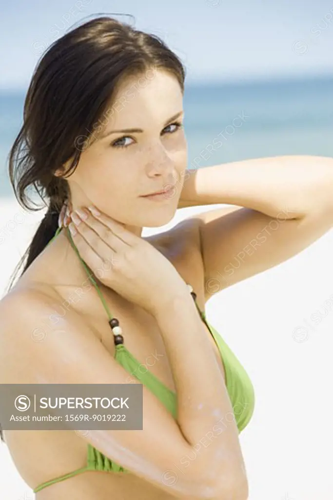 Young woman on beach, applying suntan lotion