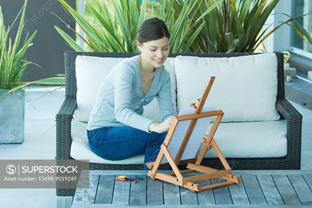 Young woman drawing with easel