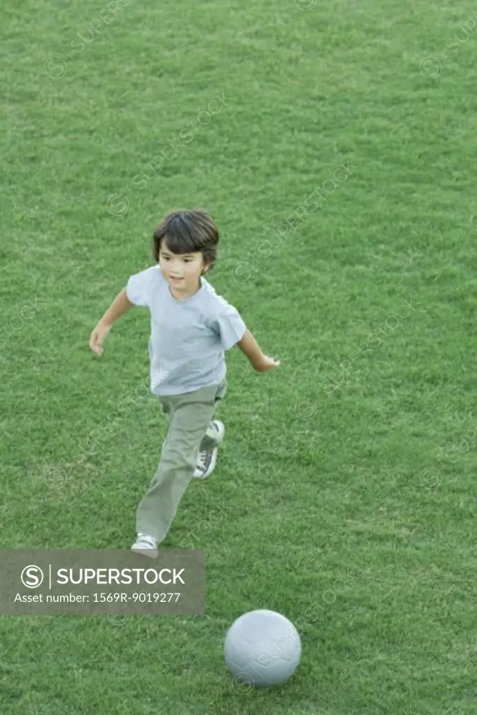Boy playing soccer on grass, high angle view, full length