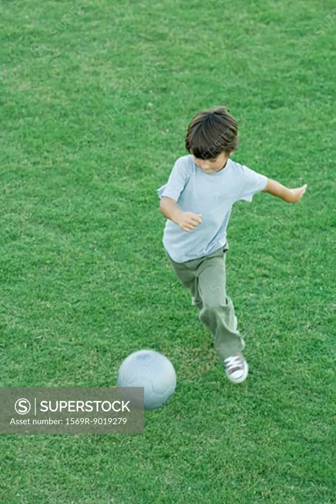 Boy playing soccer on grass, high angle view, full length
