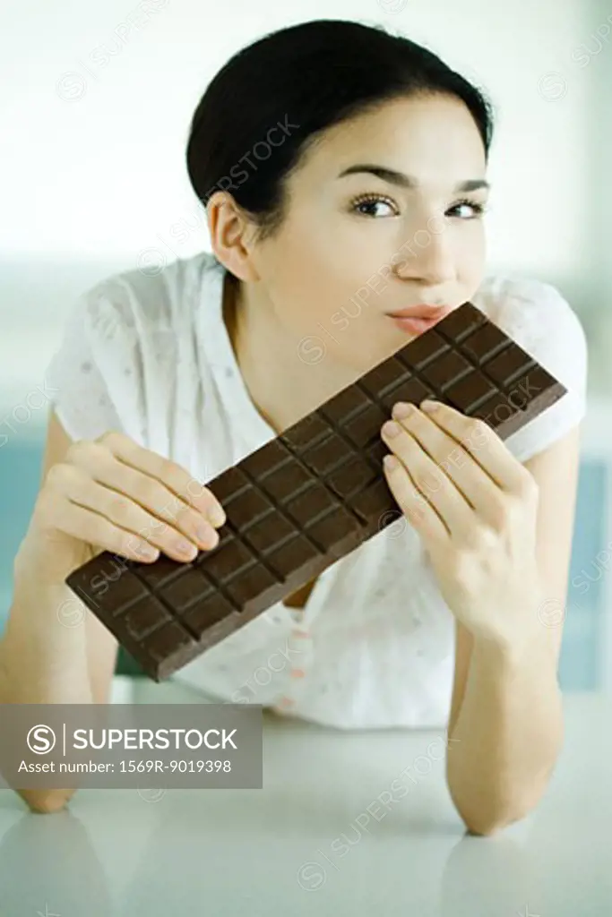 Woman holding large bar of chocolate and puckering lips