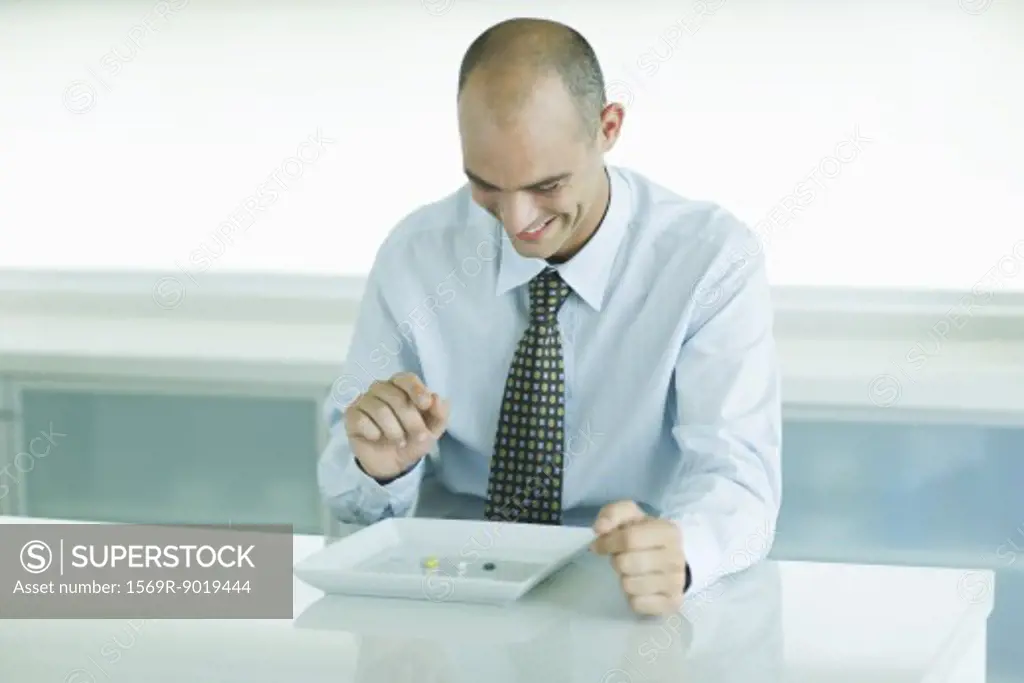 Man sitting in front of plate containing vitamins