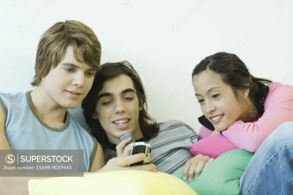Three teen friends, looking at cell phone