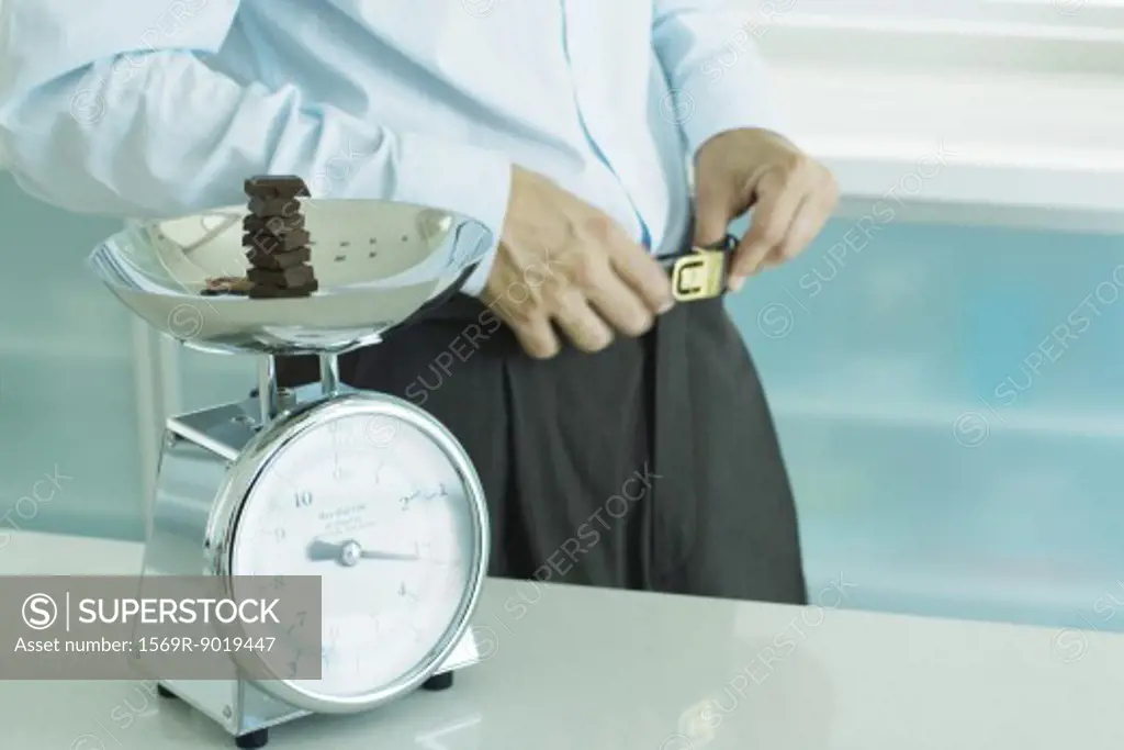 Man standing by scale containing chunks of chocolate on kitchen scale