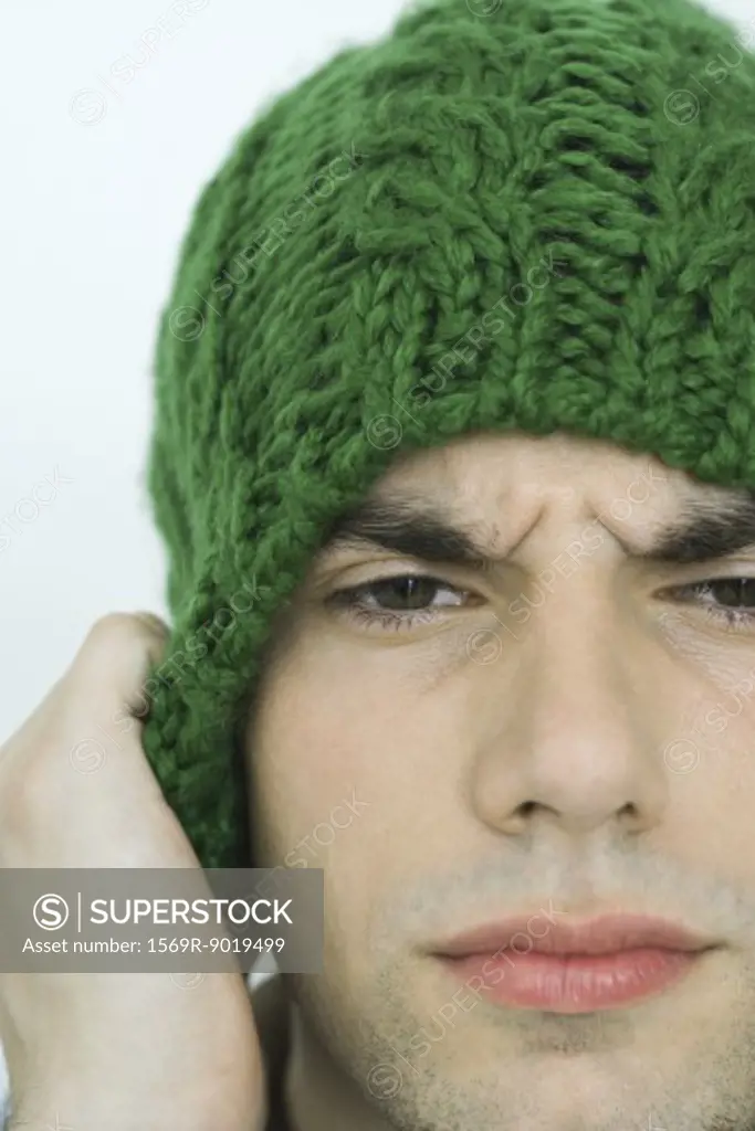 Young man wearing knit hat, furrowing brow, portrait, close-up