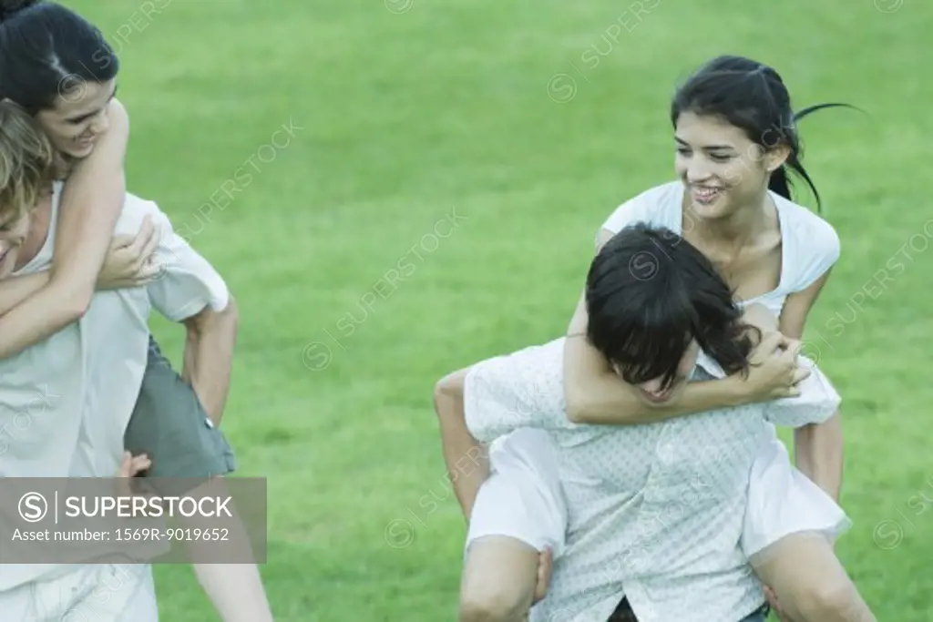 Two young couples, girlfriends being carried piggyback