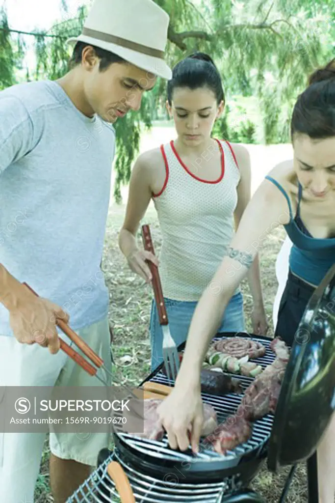Family grilling meat on barbecue