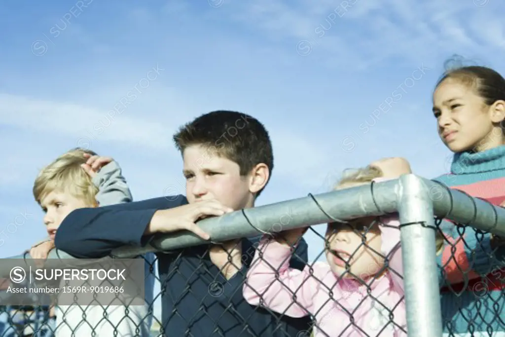Children standing behind fence