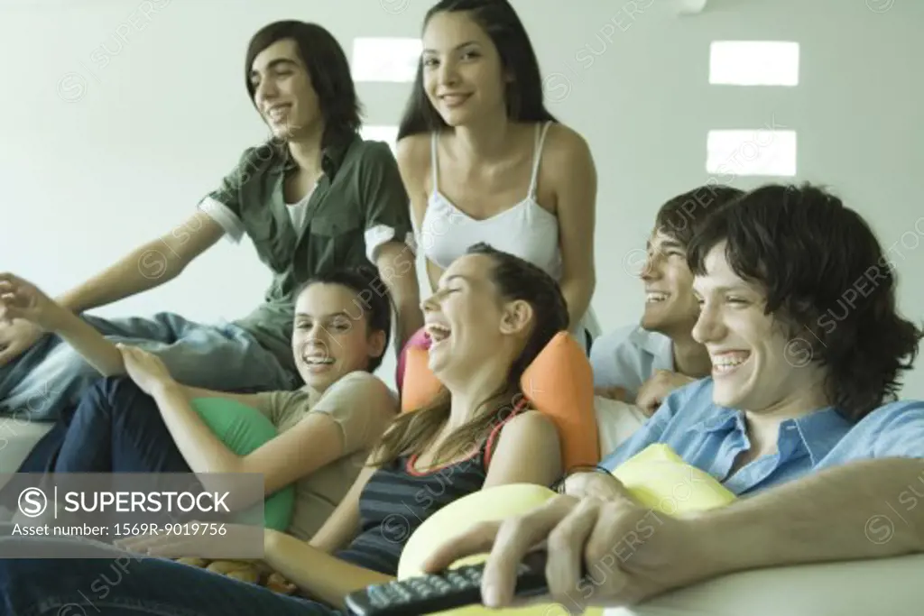 Group of young friends sitting on sofa, watching TV