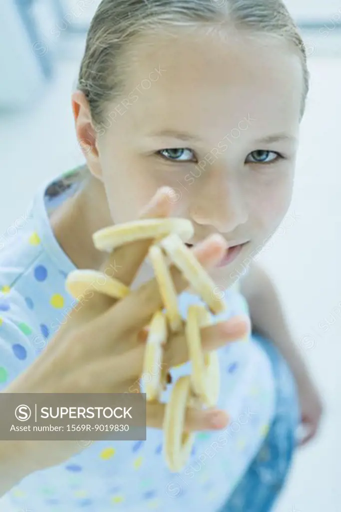 Girl holding round cookies on fingers, looking at camera