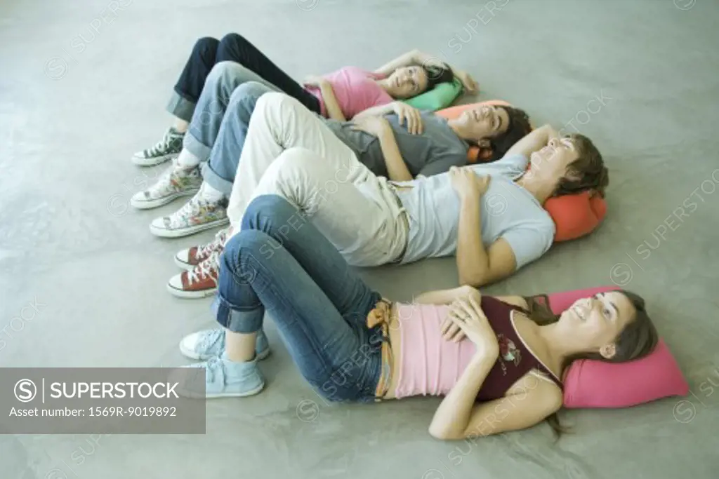 Four teen friends lying on backs on floor with knees up