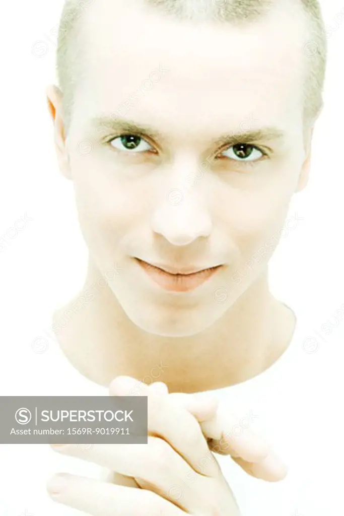 Young man clasping hands, looking at camera