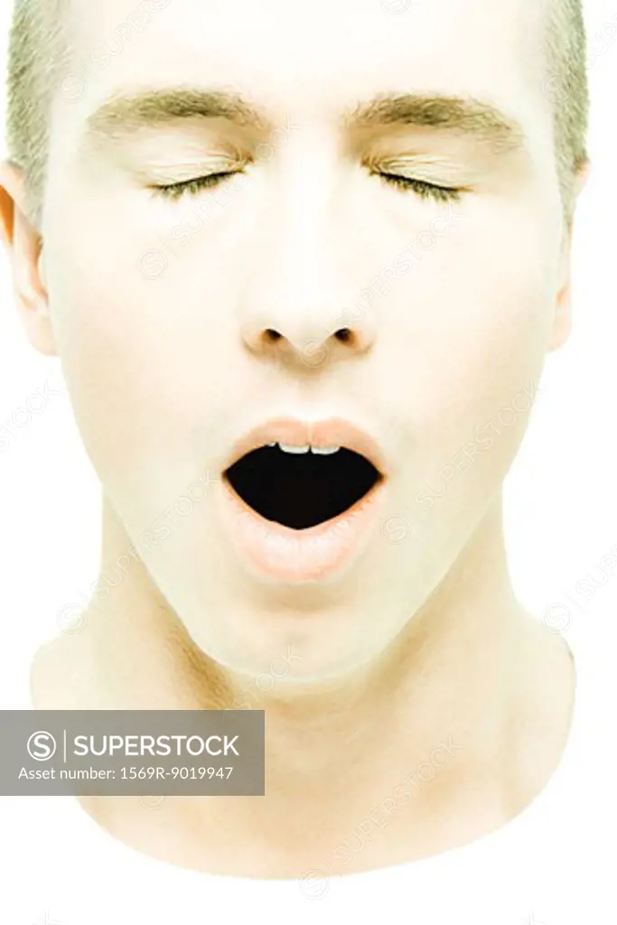 Young man yawning, eyes closed