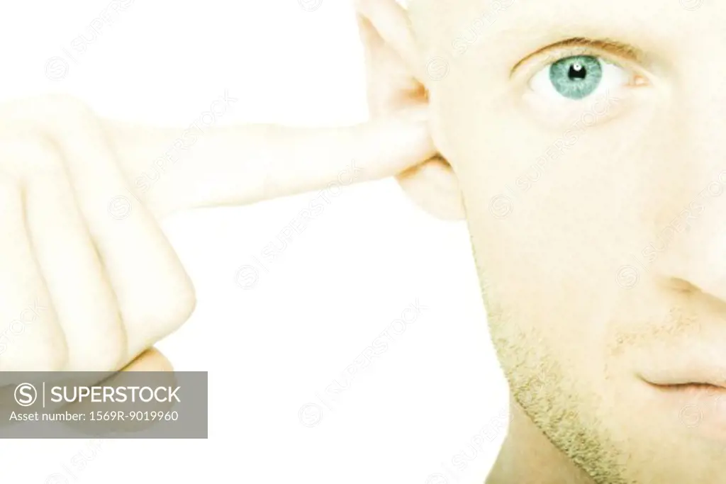 Young man plugging ear with finger
