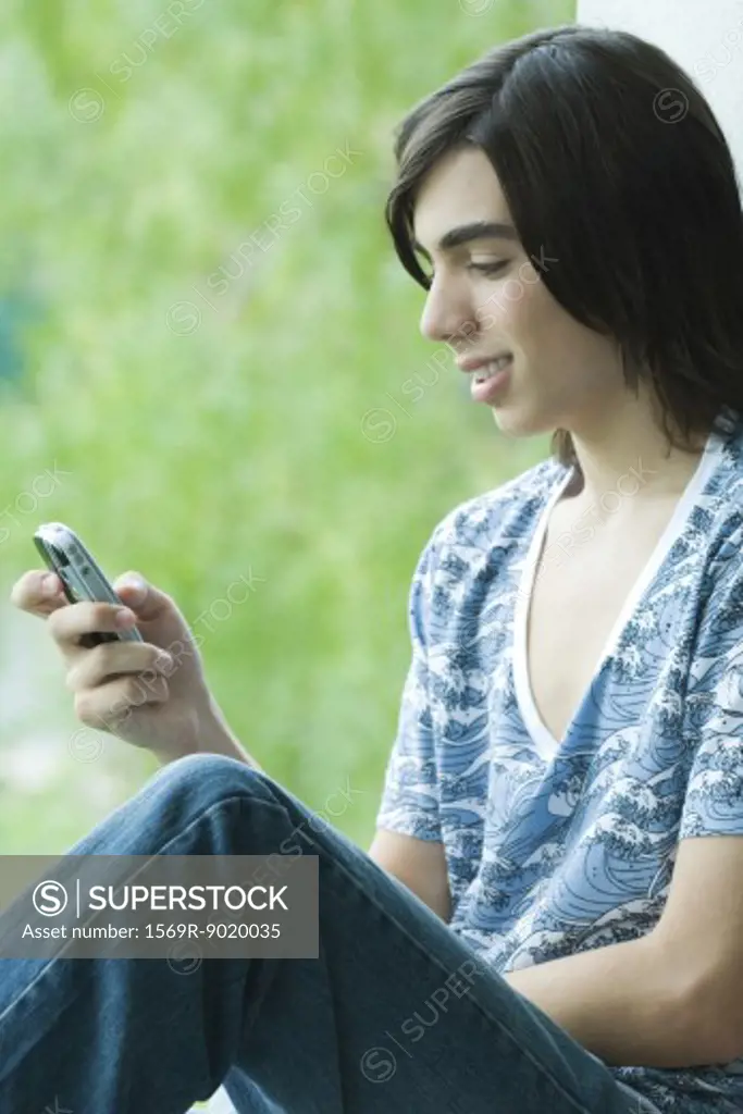 Teen boy looking at cell phone, smiling