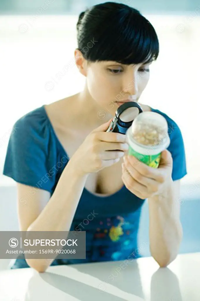 Woman looking at yogurt through magnifying glass