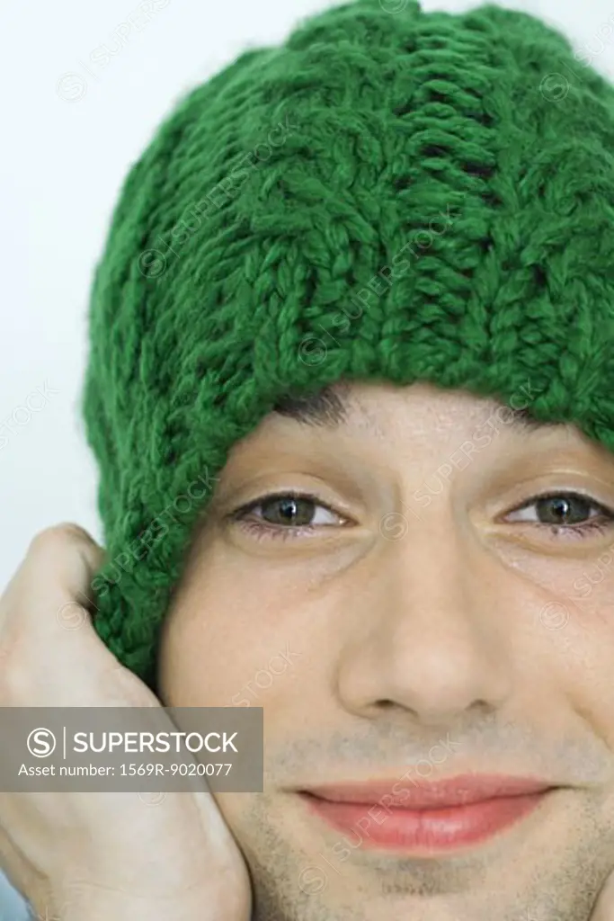 Young man pulling down knit hat over ears, portrait, close-up