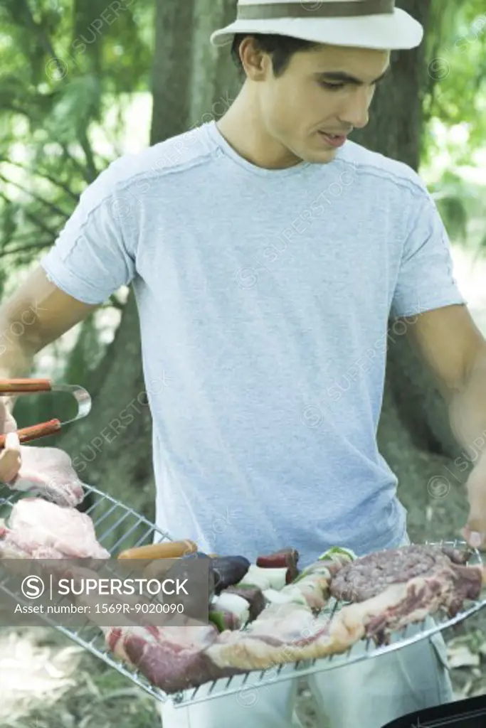 Man holding rack of meats to be grilled