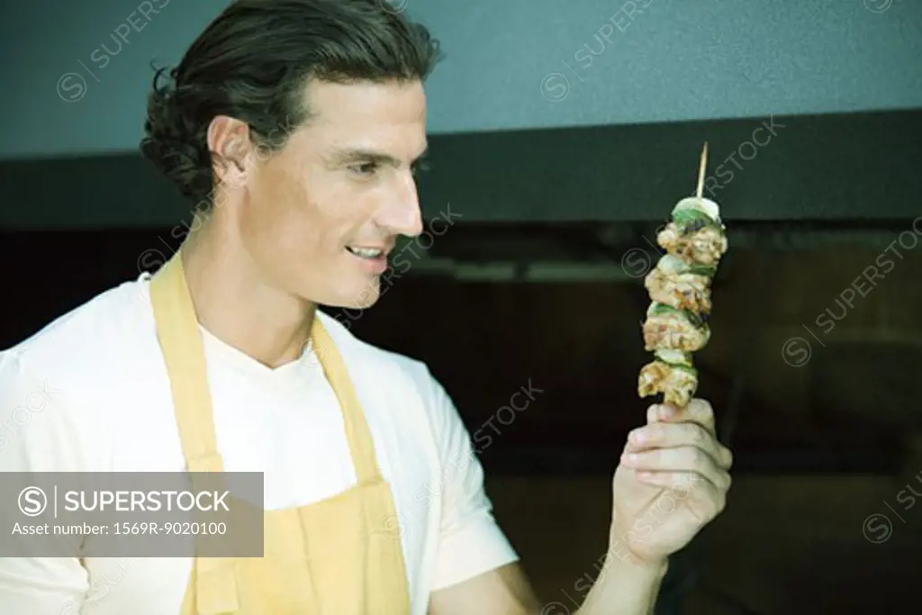 Man holding up grilled kebab