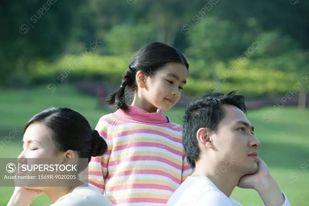 Girl looking at parents sitting back to back