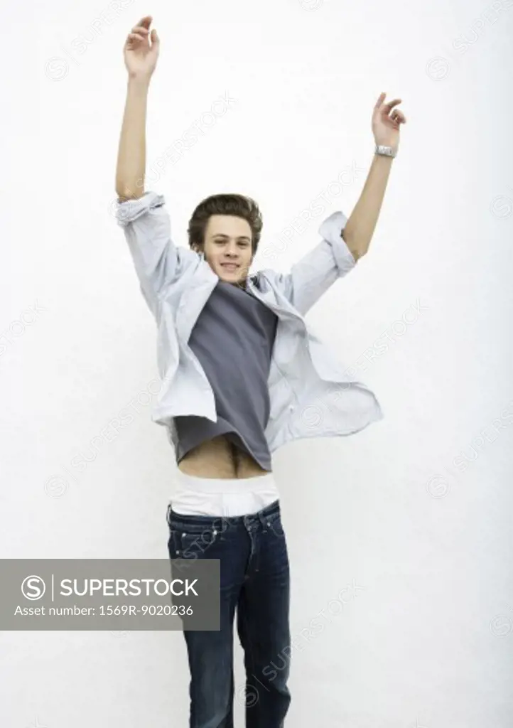 Young man jumping with arms in air
