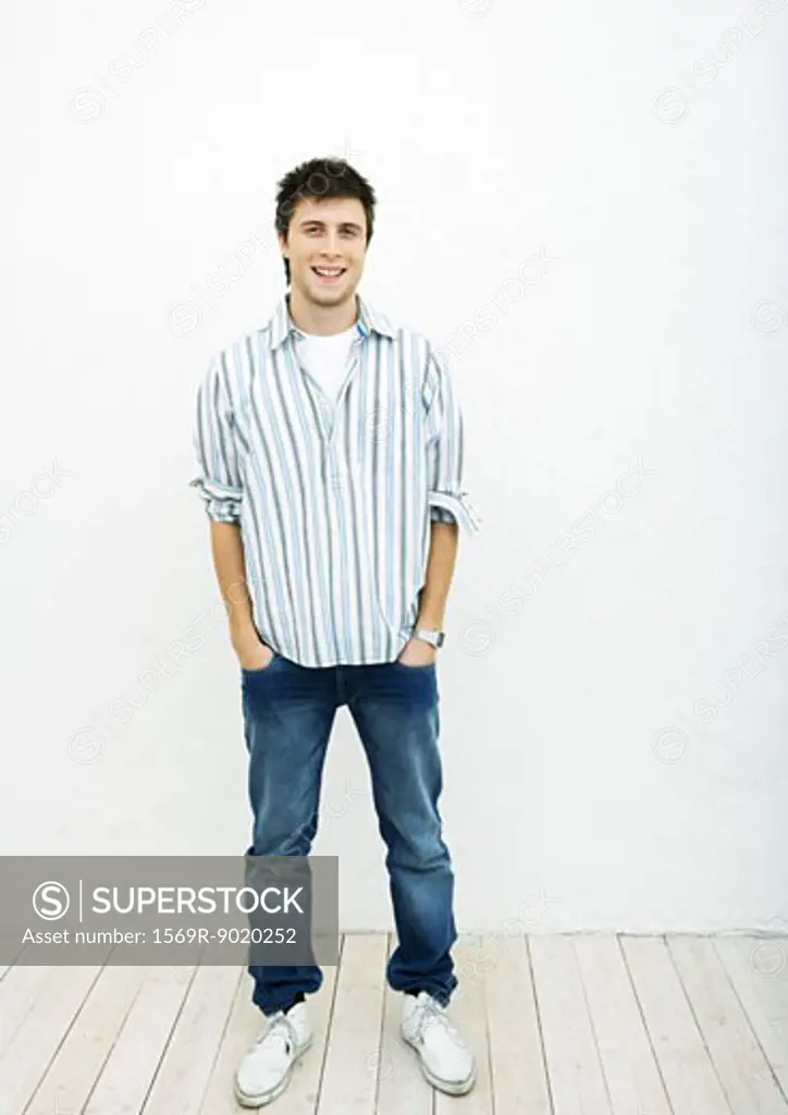 Young man standing with hands in pockets, full length portrait