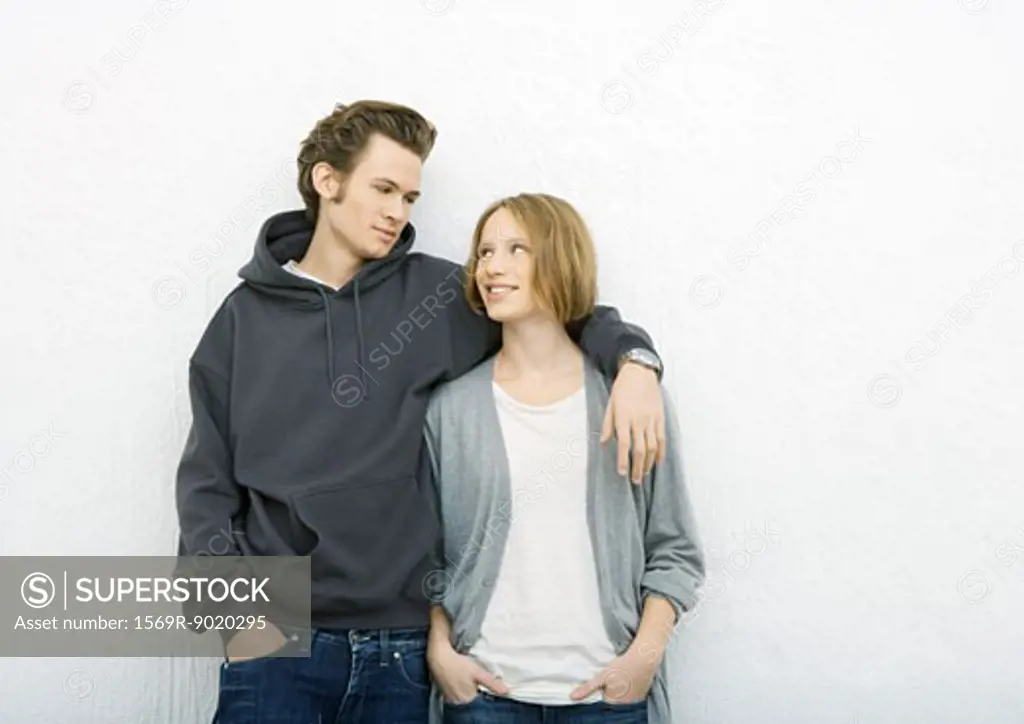 Young couple, man with arm around woman's shoulder, woman looking up at him