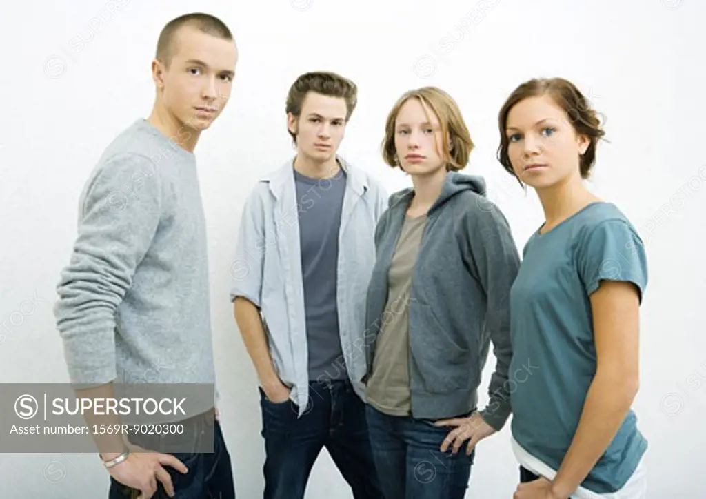 Group of young adults standing with hands on hips, looking at camera