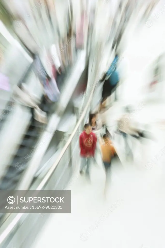 People walking in public space next to escalator, blurred motion