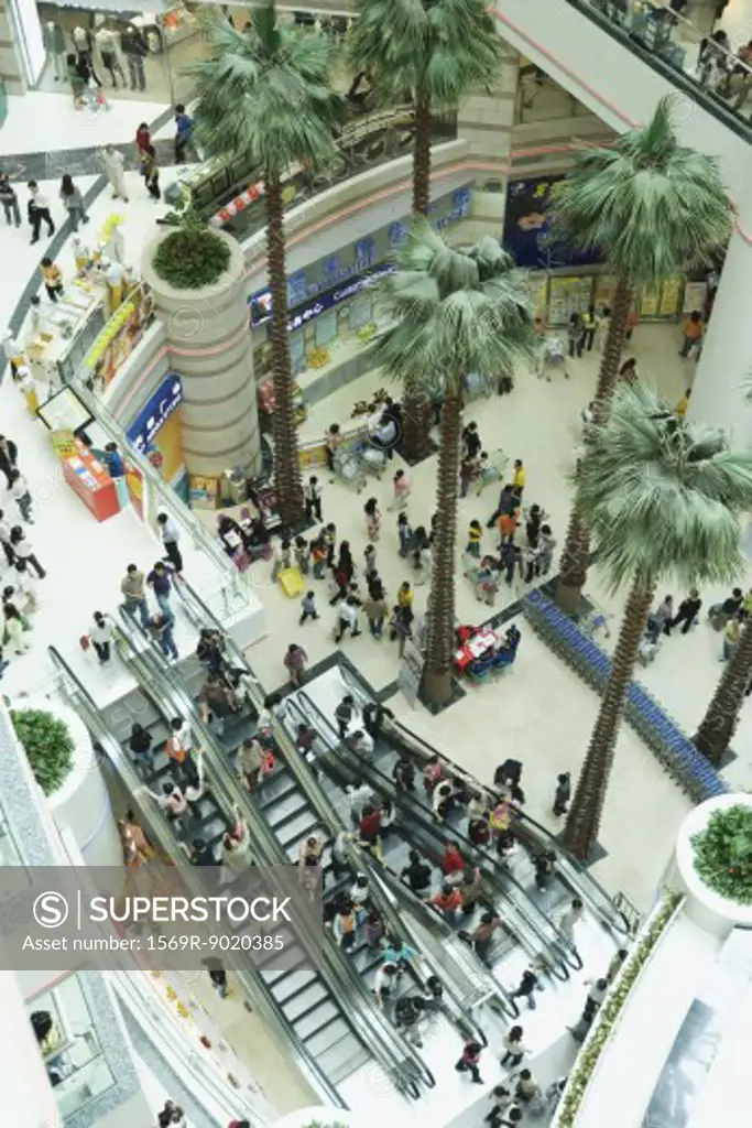 People taking escalators in shopping mall, high angle view