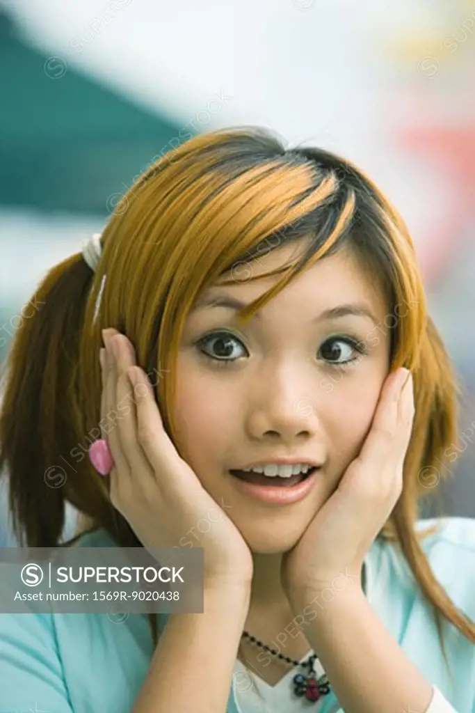 Teenage girl holding head, looking at camera