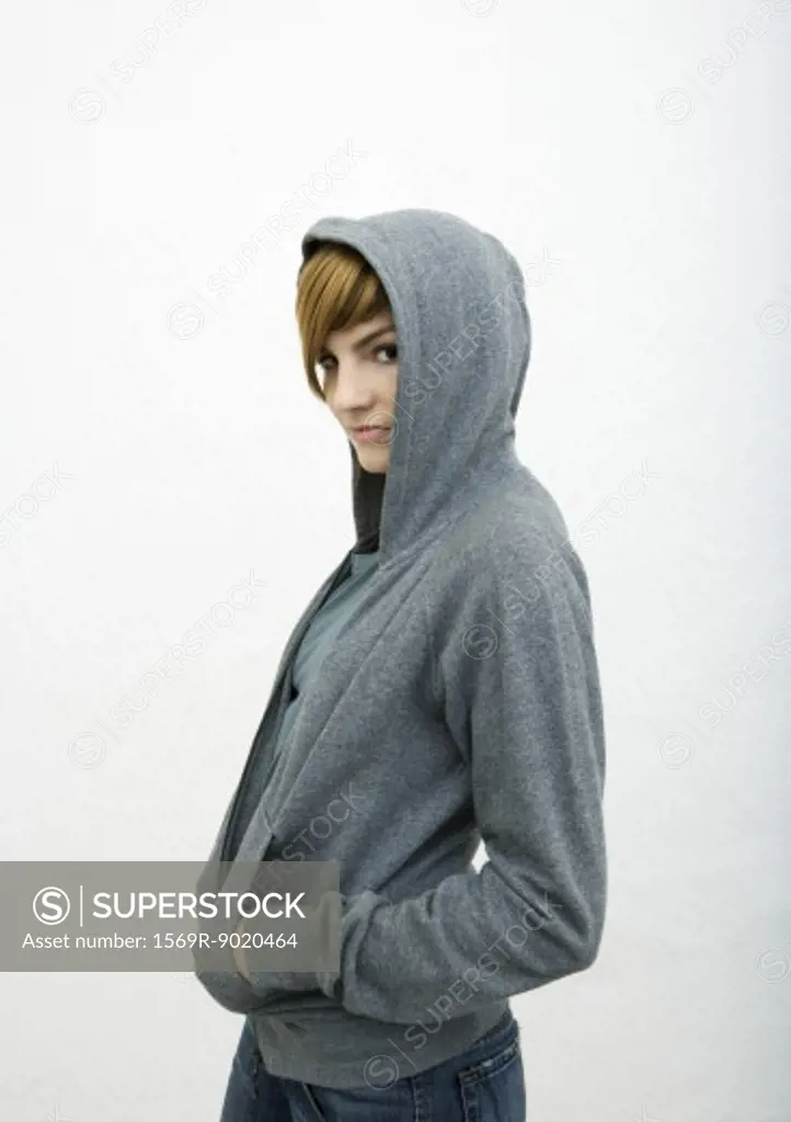 Young woman standing with hands in sweatshirt pockets