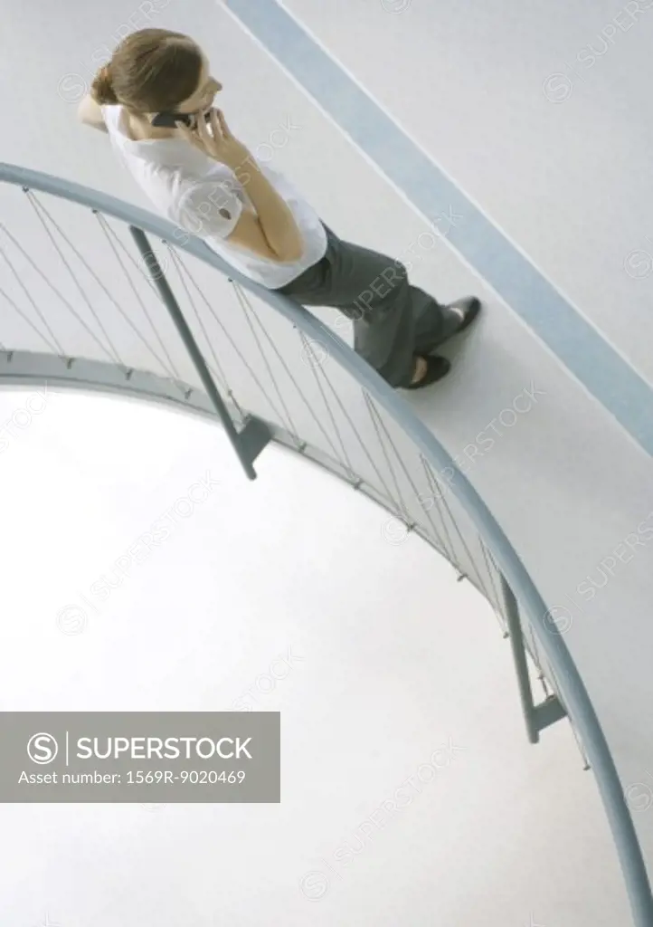 Woman leaning against railing, using cell phone, full length, high angle view