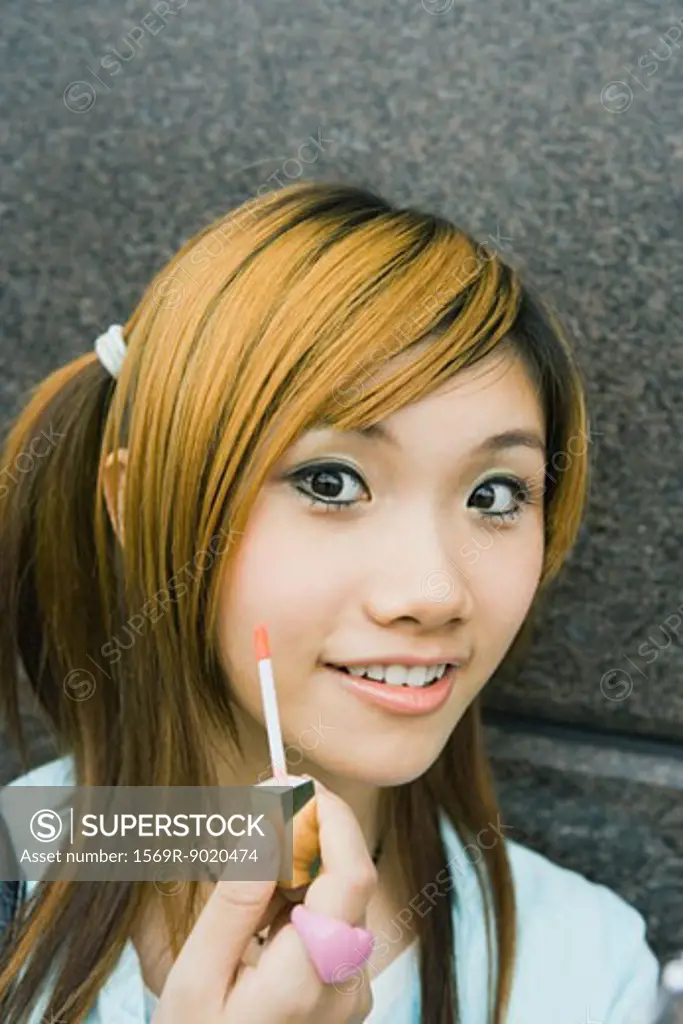 Teenage girl holding lipgloss wand