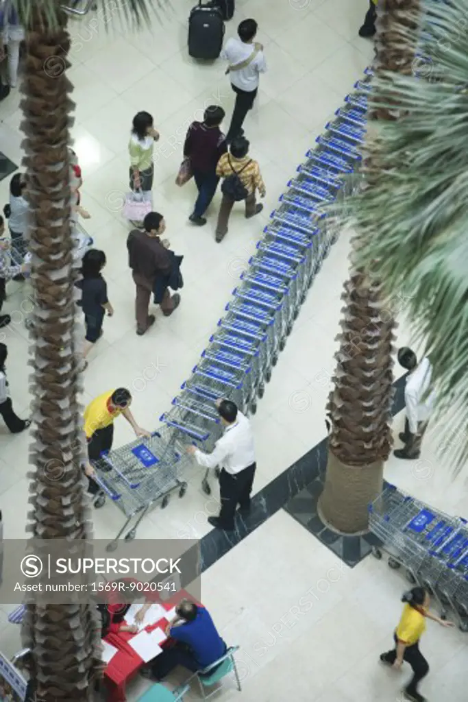 Men standing next to line of shopping carts, high angle view